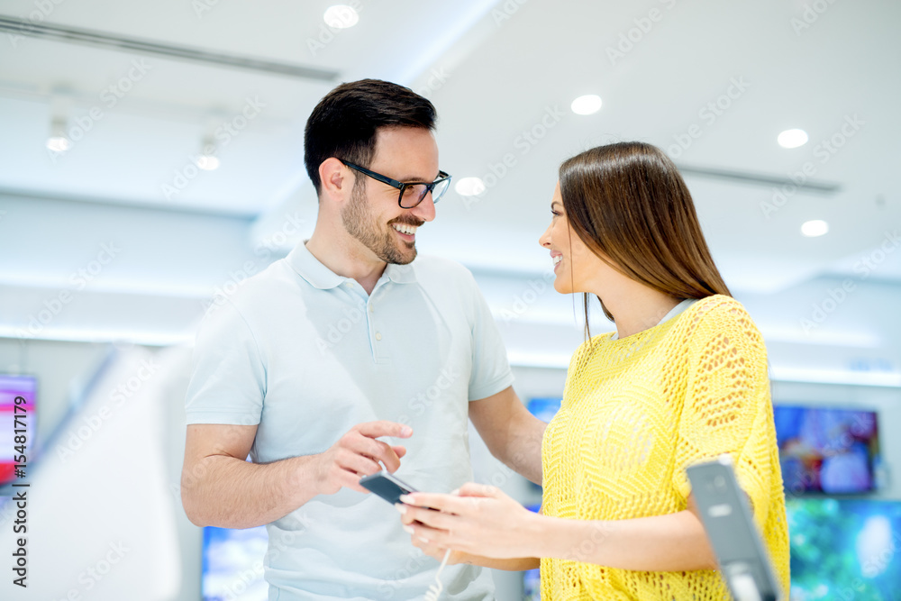 Obraz premium Happy couple buying new smart phone in tech store. 