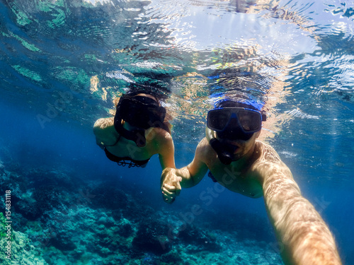 Young couple diving in clear ocean water. Honeymoon full of adventures and joy.