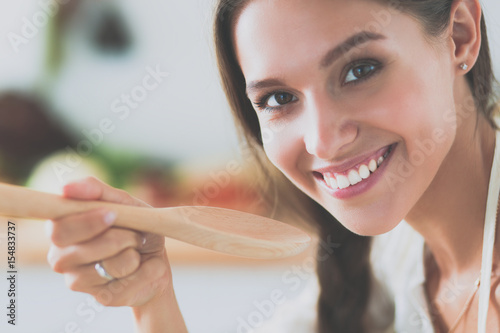 Cooking woman in kitchen with wooden spoon