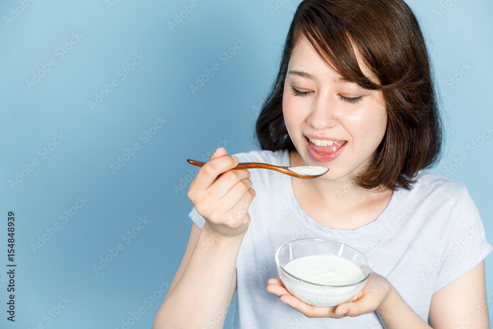 young woman eating yogurt on blue background. Probiotics concept. Intestinal flora. young woman eating yogurt on blue background. Probiotics concept. Intestinal flora.