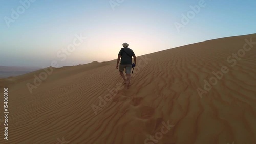 Man walking up sand dunes of Liwa desert