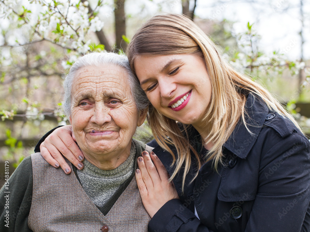 Elderly woman with cheerful caregiver outdoor, springtime Elderly woman with cheerful caregiver outdoor, springtime