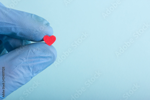 A new life in the hand of a doctor. A gloved hand hold hearts.