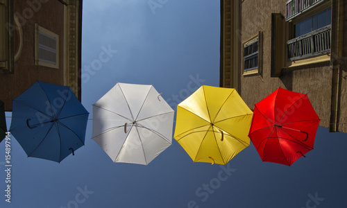 umbrellas of different colors over the street with blue sky as background