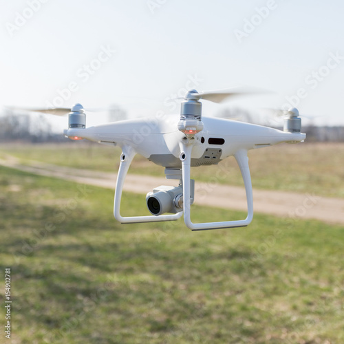 Copter soars from the ground to the sky against a background of green grass on the field. A drone with a high-resolution camera.
