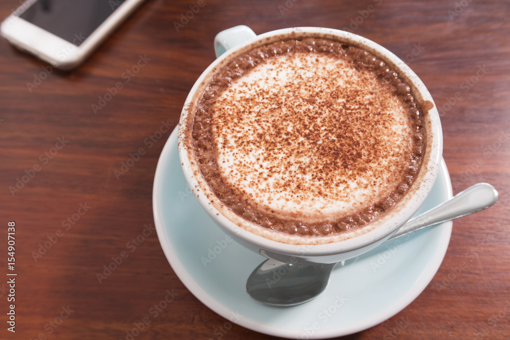 a mug of hot chocolate and smart phone on wooden table. top view. a mug of hot chocolate and smart phone on wooden table. top view.