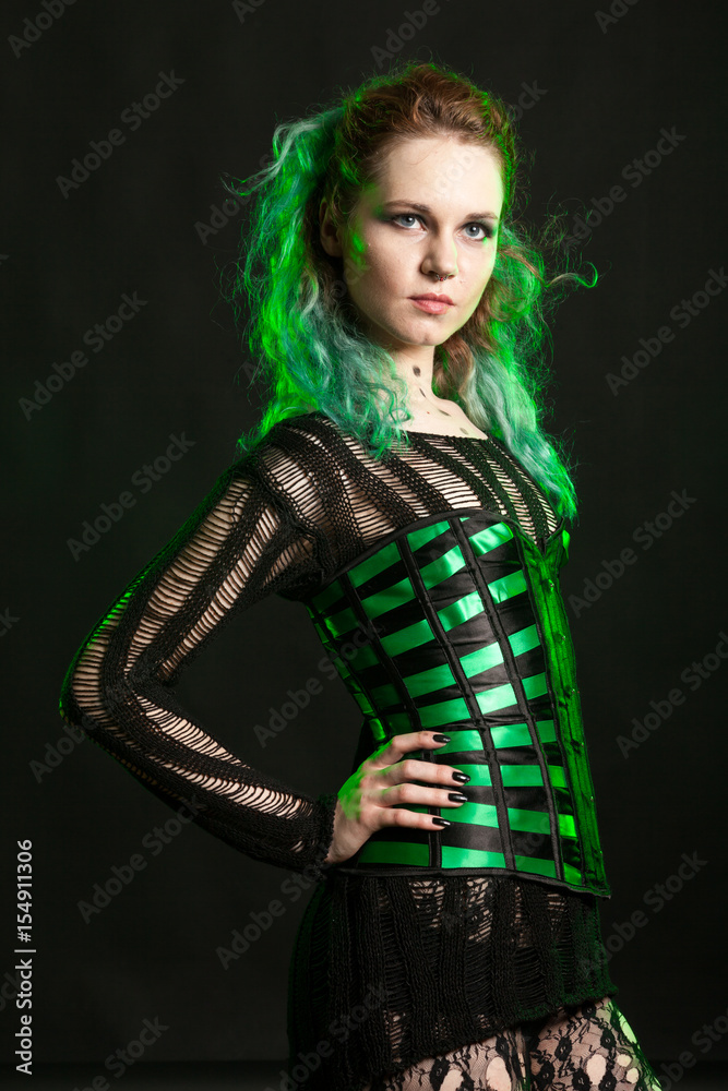 Sexy Woman in cosplay corset posing in studio with a green light from behind. Studio photo. Fashion and cosplay Sexy Woman in cosplay corset posing in studio with a green light from behind. Studio photo. Fashion and cosplay