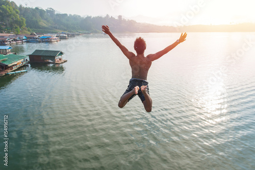 Canvas Print Man jumping into lake retro on Longest wooden bridge in sangkhlaburi Thailand