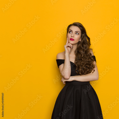 Elegant Young Woman In Black Dress Is Thinking And Looking Up