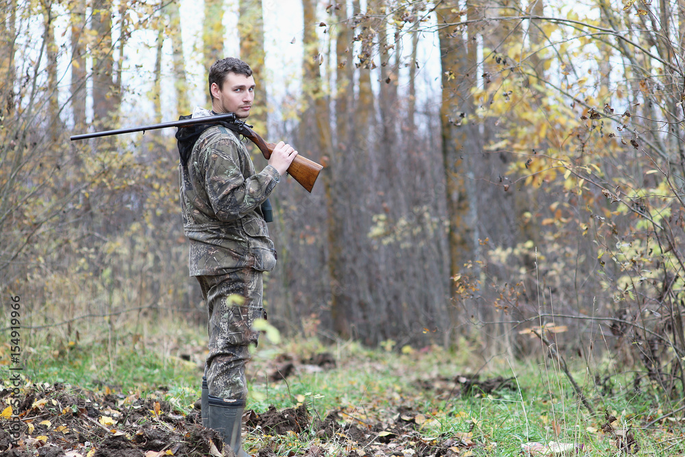 Naklejka premium Man in camouflage and with guns in a forest belt on a spring hunt