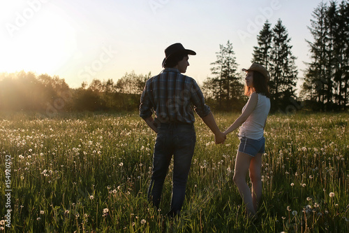 couple of young people walking in the sunset spring evening in a field