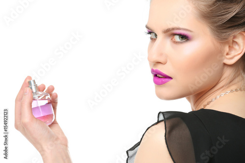 Beautiful young woman with bottle of perfume on white background