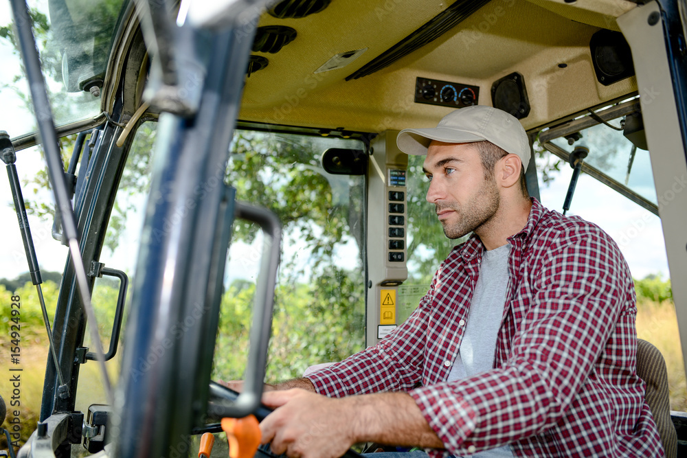 handsome young male farmer driving his tractor during harvest in the field countryside handsome young male farmer driving his tractor during harvest in the field countryside