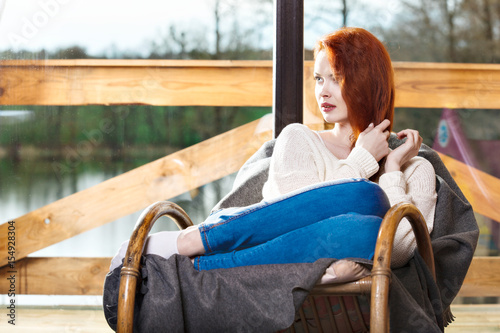 Atractive red-haired woman resting sitting on Rocking chair in f