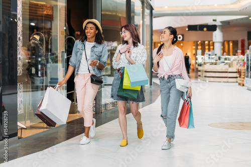 Stylish young smiling women walking with shopping bags, young girls shopping concept photo