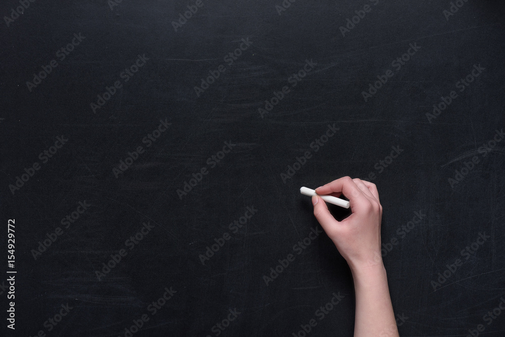 Naklejka premium human hand writing with piece of chalk on black chalkboard