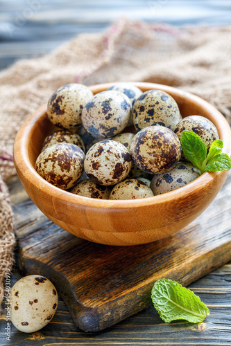 Motley quail eggs in a wooden bowl.