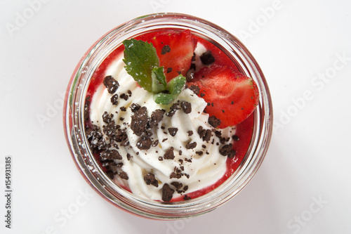 Original unusual berry dessert with honey tuille, raspberry and cream, decorated with strawberries, blueberries, cream, BlackBerry, jam with berries, rose petals on a white plate on a black background