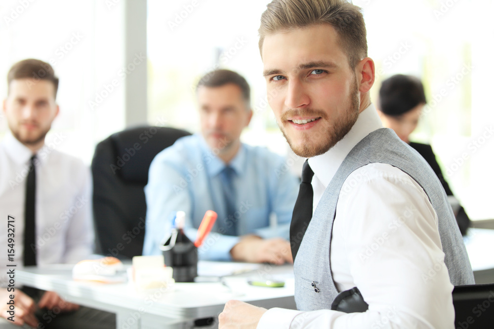 Happy smart business man with team mates discussing in the background. Happy smart business man with team mates discussing in the background.