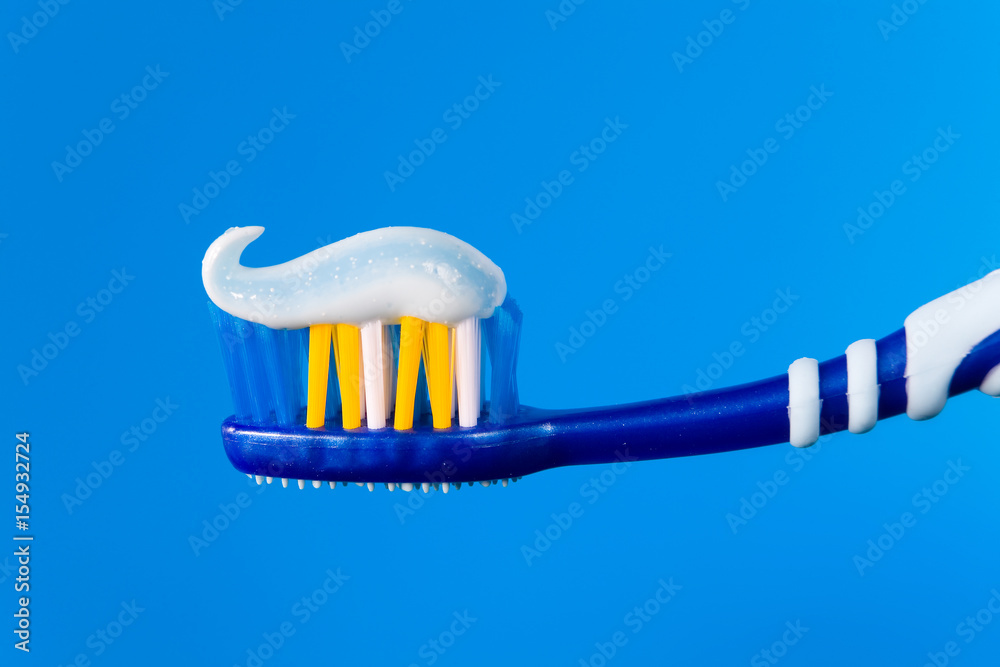Blue toothbrush with blue toothpaste on a blue background.