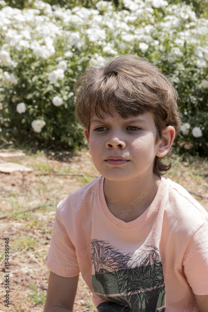 Close face of cute boy outdoor flowers in background Close face of cute boy outdoor flowers in background