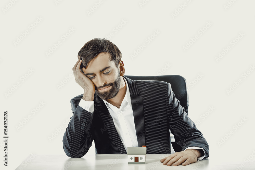 Businessman with a mini house in the office. Businessman with a mini house in the office.