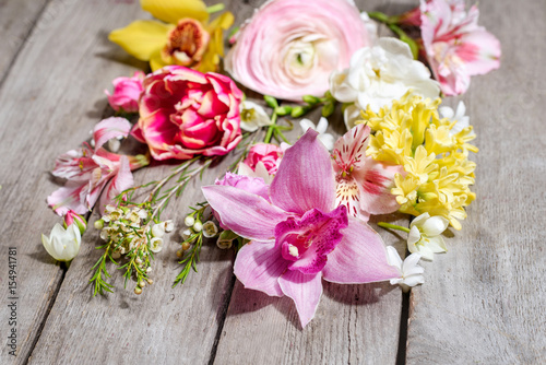 Close-up view of beautiful various blooming flowers on wooden table