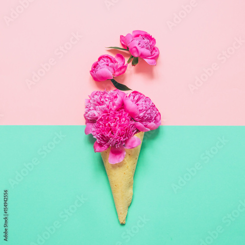 Ice cream cone with pink flowers and leaves on pink and blue background