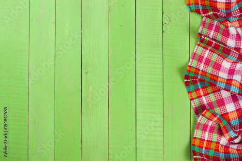 Red checkered tablecloth on a green wooden table with copy space for your text. Top view