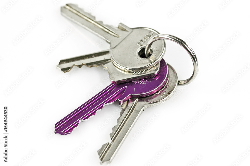 Four modern keys including one purple one on a chain isolated on a white surface.