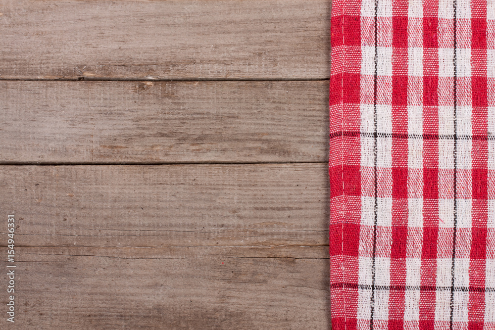 Red checkered tablecloth on an old wooden table with copy space for your text. Top view Red checkered tablecloth on an old wooden table with copy space for your text. Top view