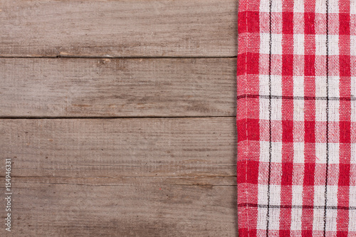 Red checkered tablecloth on an old wooden table with copy space for your text. Top view