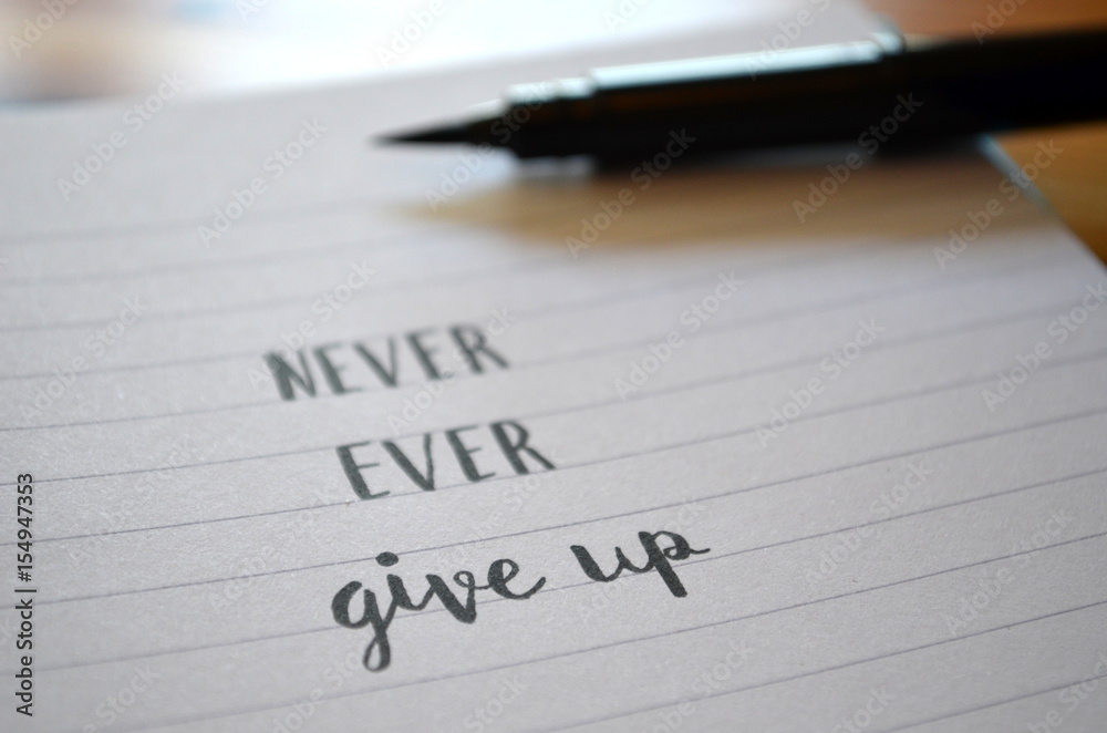 Motivational quote NEVER, EVER GIVE UP hand lettered in notebook Motivational quote NEVER, EVER GIVE UP hand lettered in notebook