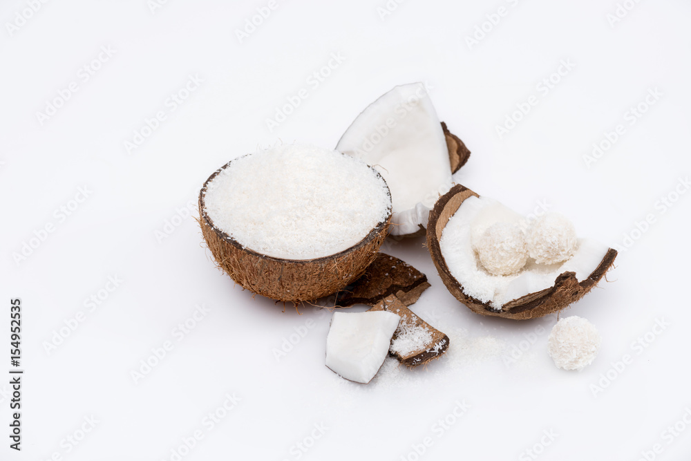 Close-up view of ripe coconut with shavings and sweet tasty candies isolated on white Close-up view of ripe coconut with shavings and sweet tasty candies isolated on white