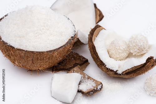 Close-up view of ripe coconut with shavings and sweet tasty candies isolated on white