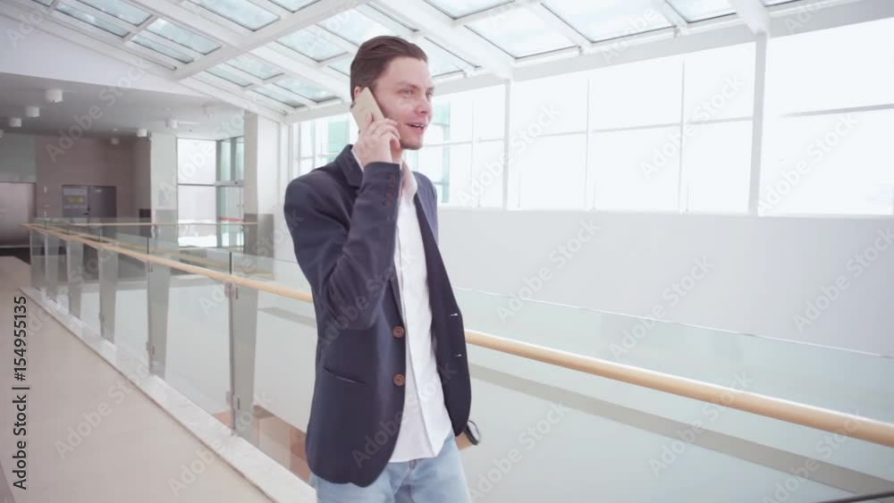 Portrait of young businessman with coffee and smart phone in modern glass office on background. Business man using gadget on his working break Portrait of young businessman with coffee and smart phone in modern glass office on background. Business man using gadget on his working break