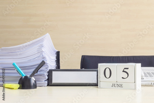 Closeup white wooden calendar with black 5 june word on blurred brown wood desk and wood wall textured background in office room view with copy space , selective focus at the calendar