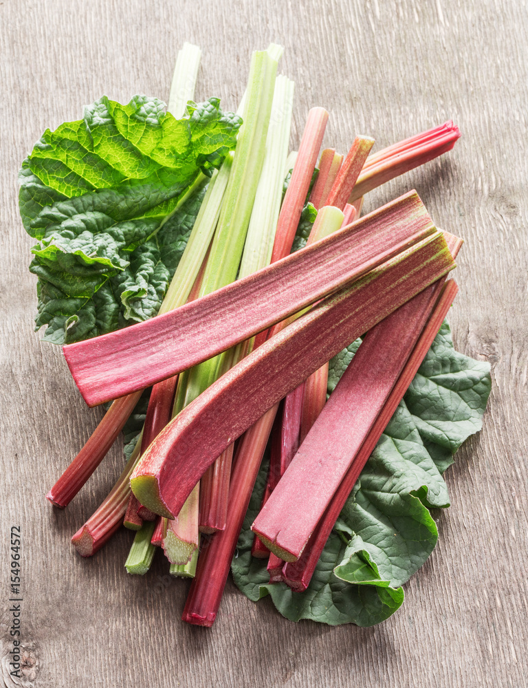 Edible rhubarb stalks on the wooden table. Edible rhubarb stalks on the wooden table.