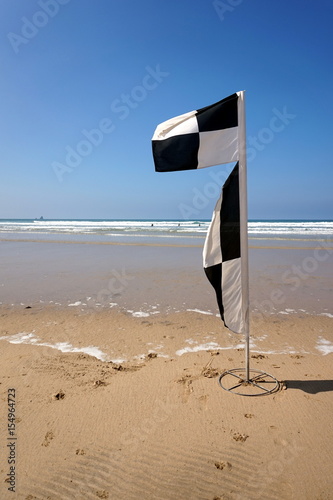 Flag on a deserted beach indicating safe swimming and surfing zones