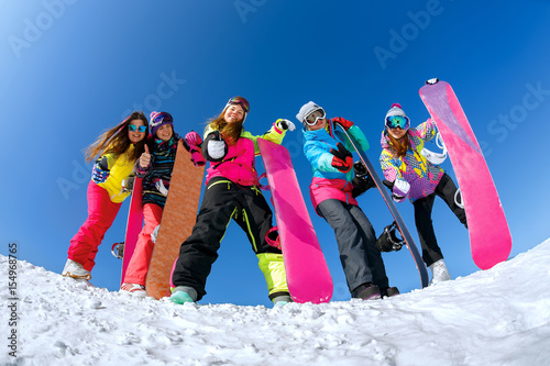 Cheerful snowboarder posing on top of a mountain