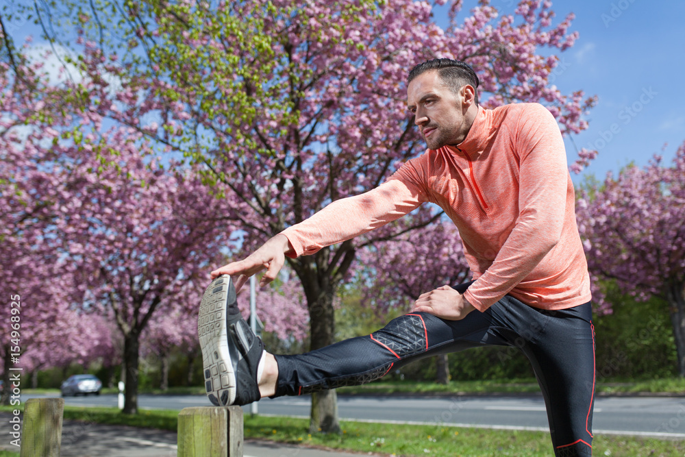 Fototapeta premium Mann dehnt sein Bein vor dem Training