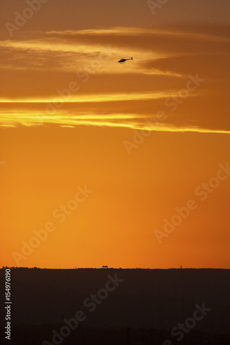 A helicopter graces the landscape during a spectacular orange sunset. © Fred