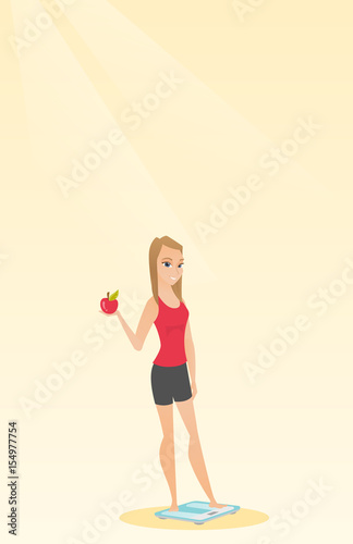 Woman standing on scale and holding apple in hand.