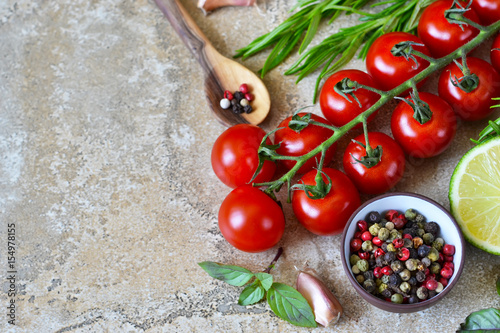 Food background with different ingredients on a marble background. Cherry tomatoes, rosemary, garlic, pepper, lime. Top view.