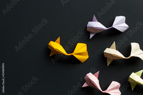 Handmade paper craft origami gold koi carp fishes on black background.Top view, pattern photo