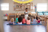 Teacher At Montessori School Reading To Children At Story Time