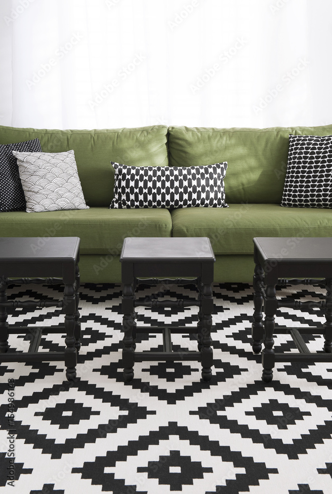 Salon avec canapé vert, coussins et tapis design noir & blanc et tabourets  noirs Stock Photo