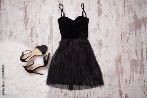 Little black dress and black shoes. Wooden background, fashionable concept photo