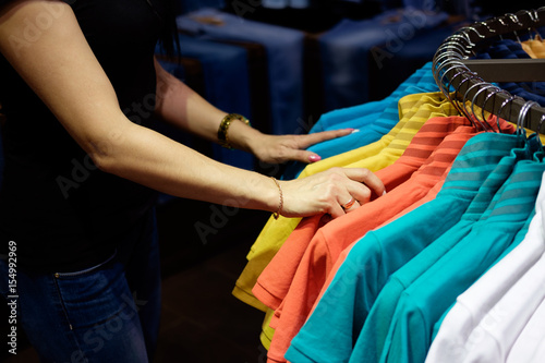 woman in clothes store choosing t-shirt, hands close up