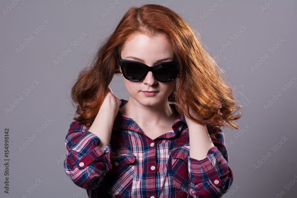 Close-up portrait of a red-haired beautiful woman wearing sunglasses Close-up portrait of a red-haired beautiful woman wearing sunglasses